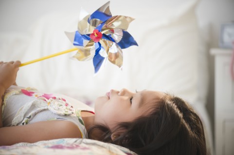 Korean girl laying on bed holding pinwheel