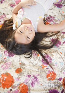 Smiling Korean girl laying on bed