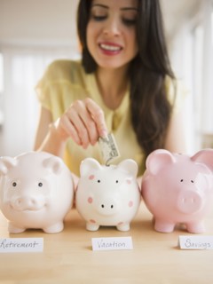 Mixed race woman putting money into piggy bank