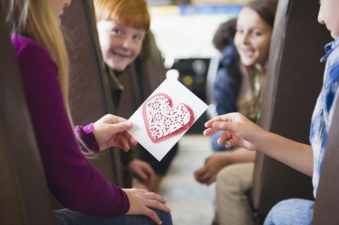 Girl giving friend Valentine on school bus