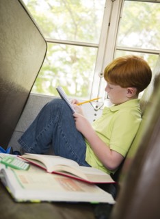 Caucasian boy doing homework on school bus