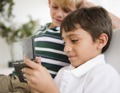 Boy watching friend playing hand-held video game