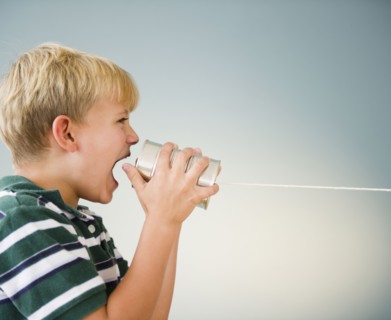 Caucasian boy shouting into tin can telephone