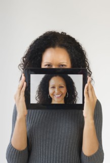 Hispanic woman holding digital tablet in front of face
