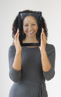 Hispanic woman holding digital tablet in front of face