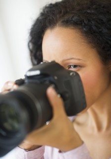 Hispanic woman taking photographs with camera