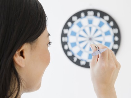 Japanese woman throwing dart at dartboard