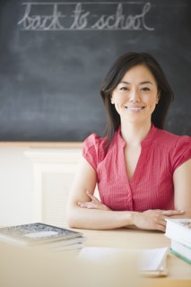 Japanese teacher sitting at desk in classroom