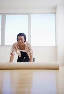 Black woman unrolling carpet in new home