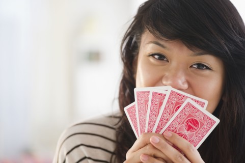 Pacific Islander woman covering her mouth with playing cards
