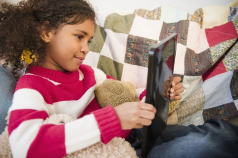 Mixed race girl sitting on sofa using digital tablet