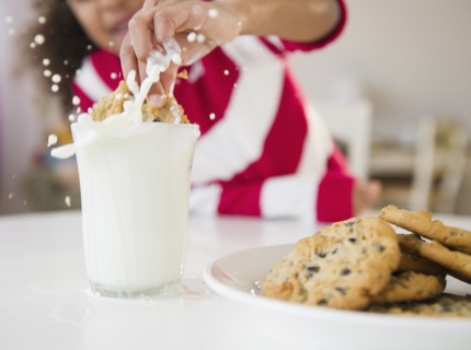 Mixed race girl dunking cookie into milk