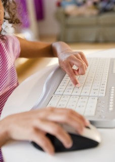 Mixed race girl using computer keyboard
