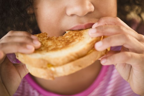 Mixed race girl eating sandwich