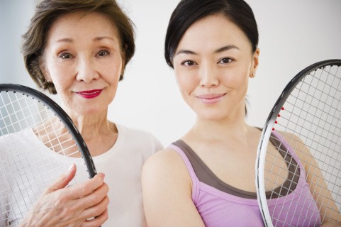 Japanese mother and daughter holding tennis racquet