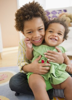 Black brother holding sister on his lap