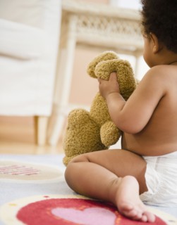 Black baby girl holding teddy bear