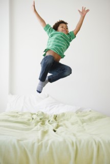 Black boy jumping on bed