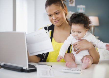 Mixed race mother holding baby and paying bills