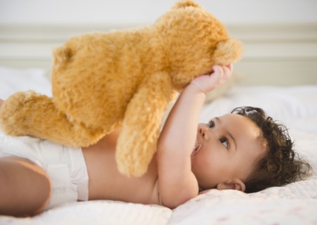 Mixed race baby holding teddy bear