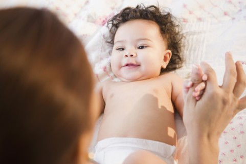 Mixed race mother holding hands with baby
