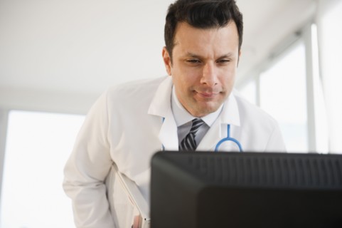 Mixed race doctor looking at computer monitor