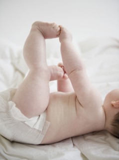 Caucasian baby girl laying on blanket holding feet