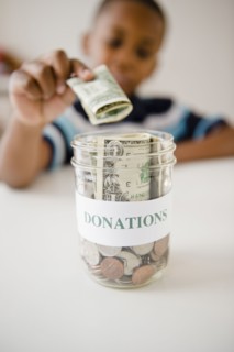 Black boy putting money into donations jar