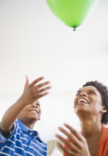 Black mother and son watching floating balloon