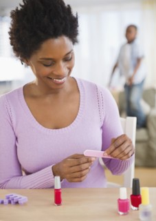 Black woman giving herself a manicure