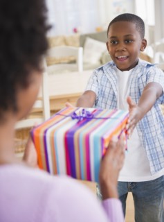 Black son handing mother a gift