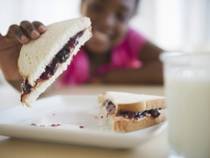 Black girl eating peanut butter and jelly sandwich