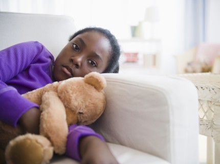 Black girl laying on sofa with teddy bear