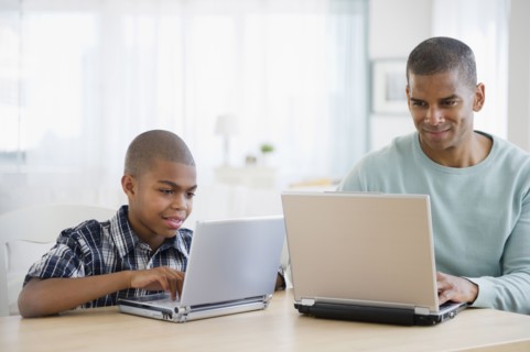 Father and son using laptops together
