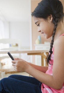 Mixed race girl text messaging on cell phone