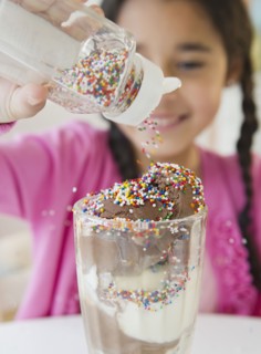 Mixed race girl putting sprinkles on ice cream