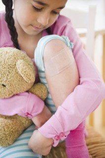 Mixed race girl looking at bandage on knee