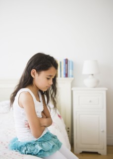 Mixed race girl sitting on bed