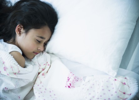 Mixed race girl sleeping in bed
