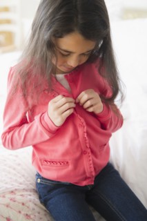 Mixed race girl buttoning her shirt