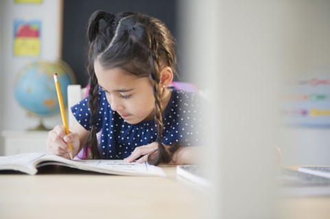 Mixed race girl writing in school