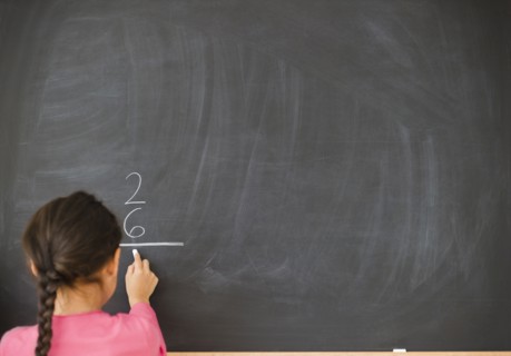 Mixed race girl doing math on blackboard