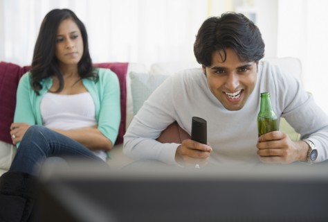 Angry girlfriend watching husband enjoy television