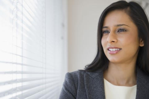 Mixed race businesswoman looking out window