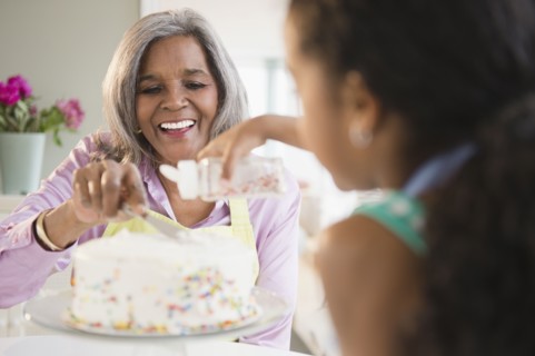 African American grandmother and granddaughter decorating a cake