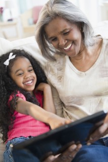 African American grandmother and granddaughter looking at digital tablet