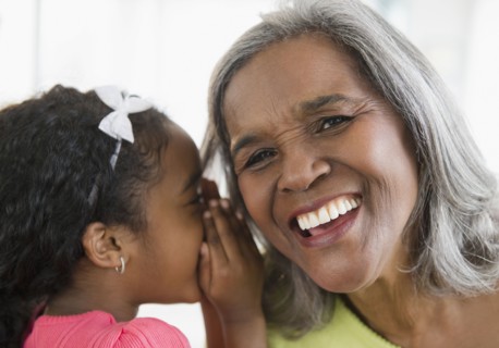 African American girl telling secret to grandmother