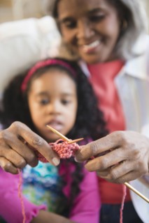 African American woman showing granddaughter how to knit