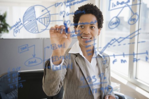 African American businesswoman writing on glass board