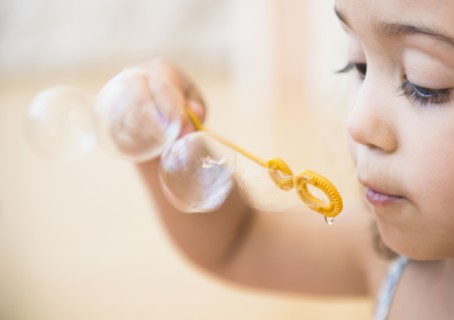 Mixed race girl blowing bubbles